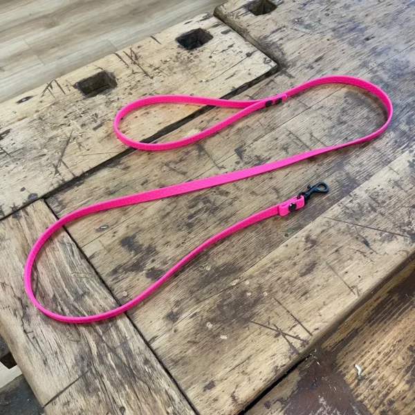 Eine Hundeleine aus dem Material Hexa. Sie ist 1 cm breit und pink. Die Hundeleine hat schwarze Karabiner und Schrauben. Außerdem hat sie am Ende eine Hand Schlaufe.