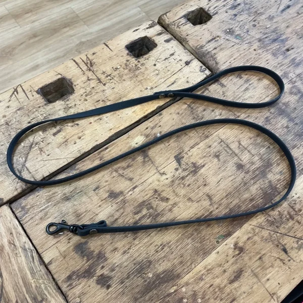 Eine Hundeleine aus dem Material Hexa. Sie ist 1 cm breit und schwarz. Die Hundeleine hat schwarze Karabiner und Schrauben. Außerdem hat sie am Ende eine Hand Schlaufe.