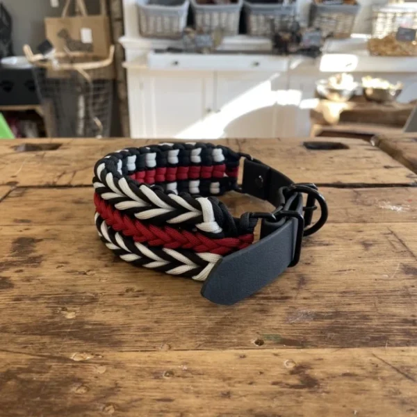 Halsband für Hunde aus dem Material Paracord. Das Halsband hat ein Biothane Adapter. Das Halsband besteht aus den Farben, schwarz rot und weiß.
