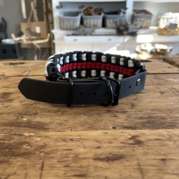 Halsband für Hunde aus dem Material Paracord. Das Halsband hat ein Biothane Adapter. Das Halsband besteht aus den Farben, schwarz rot und weiß.